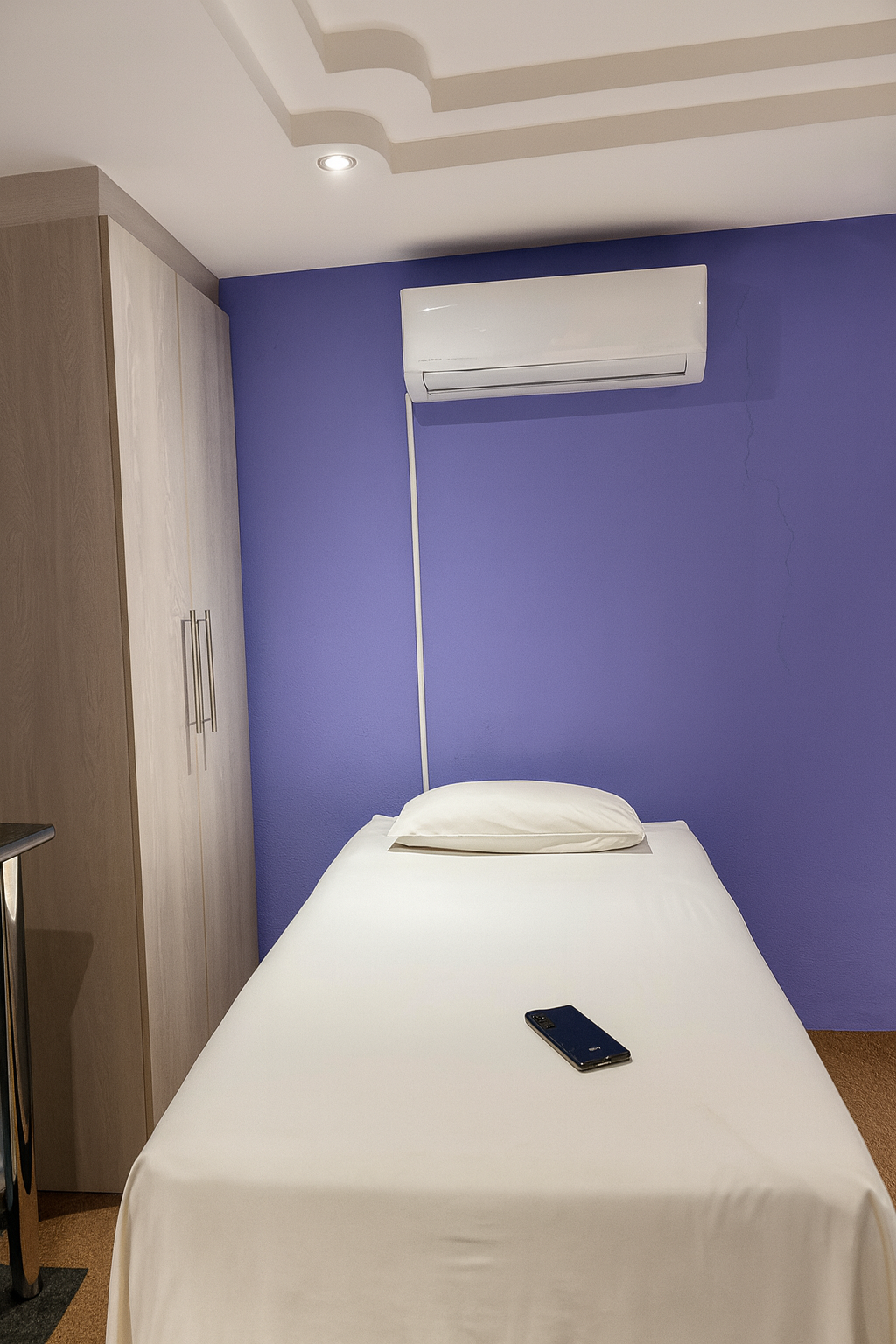 Standard room with queen bed against purple accent wall
